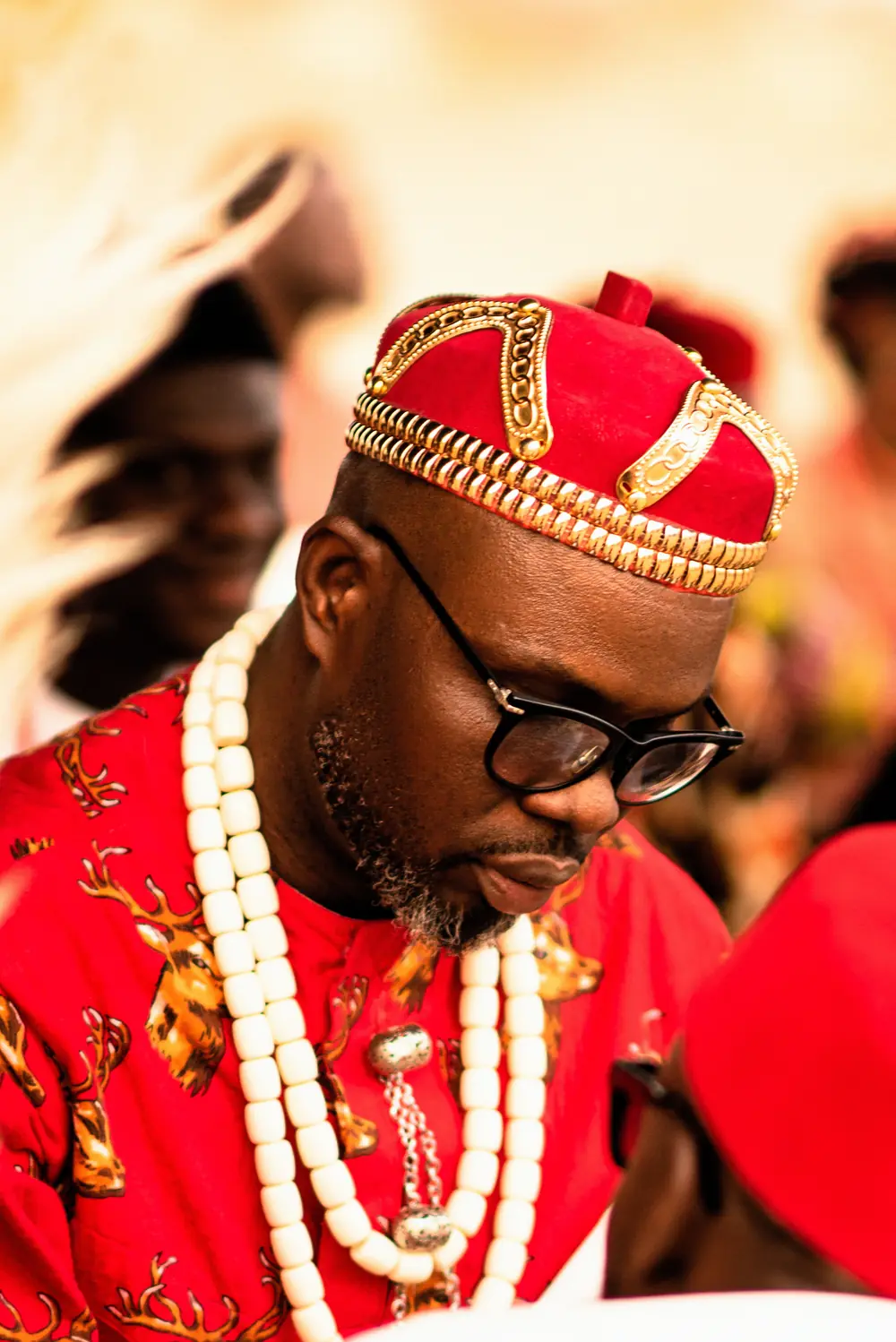 A chief in a red and gold cap with ivory beads